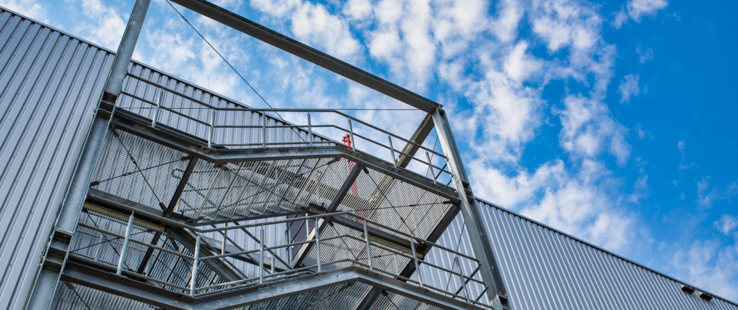 open fire escape staircase on the exterior wall of a warehouse with a sheet metal facade. Sondersituationen