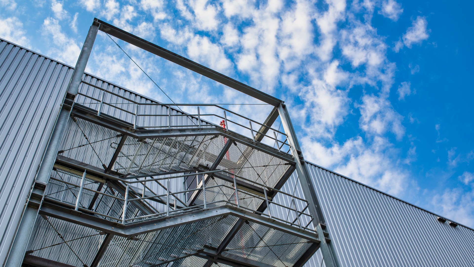 open fire escape staircase on the exterior wall of a warehouse with a sheet metal facade. Sondersituationen